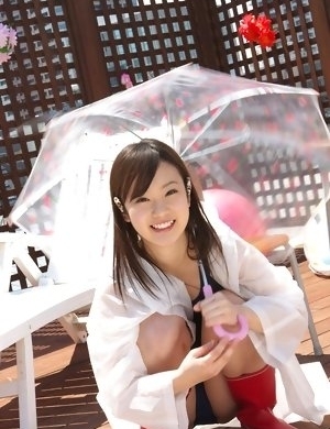 Kana Yuuki in bathsuit plays with umbrella in the balcony